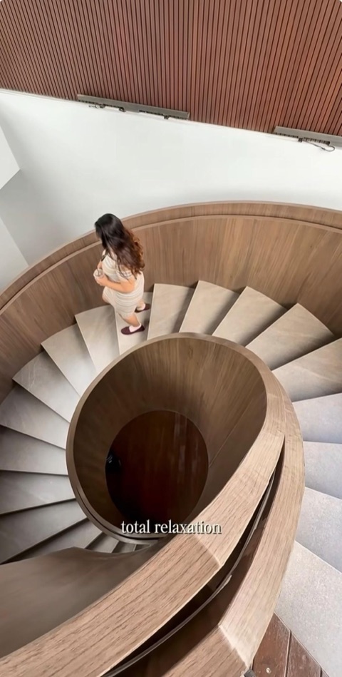 Tamu menuruni tangga spiral kayu di BugenVilla